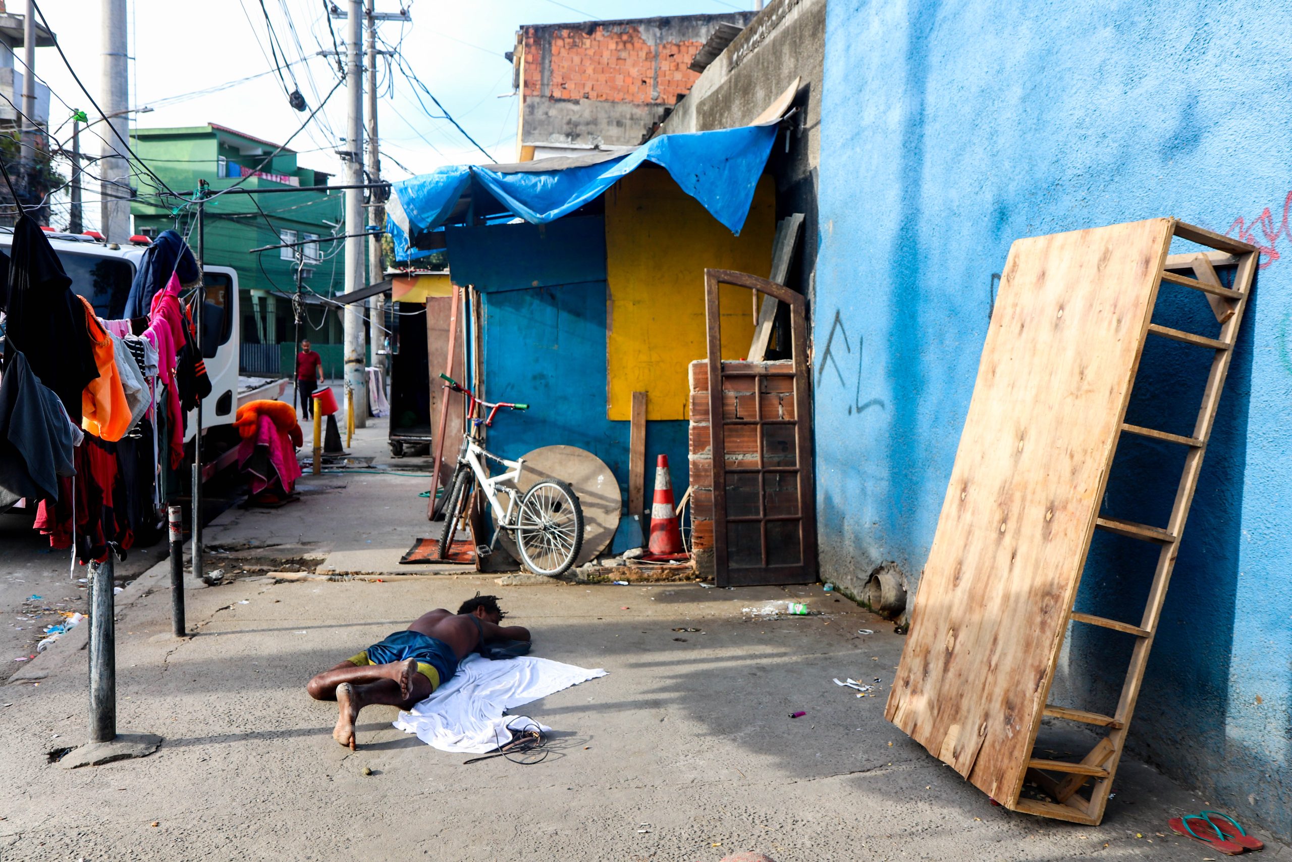 Nesta foto vemos um homem negro, que vive em situação de rua, uma realidade infelizmente ainda muito presente no Brasil. O chinelo bem sobreposto ao lado do que sobrou da cama juntamente com o lençol que cobre o chão onde ele descansa depois de um dia de coleta de resíduos  recicláveis. Foto: Vilma Ribeiro