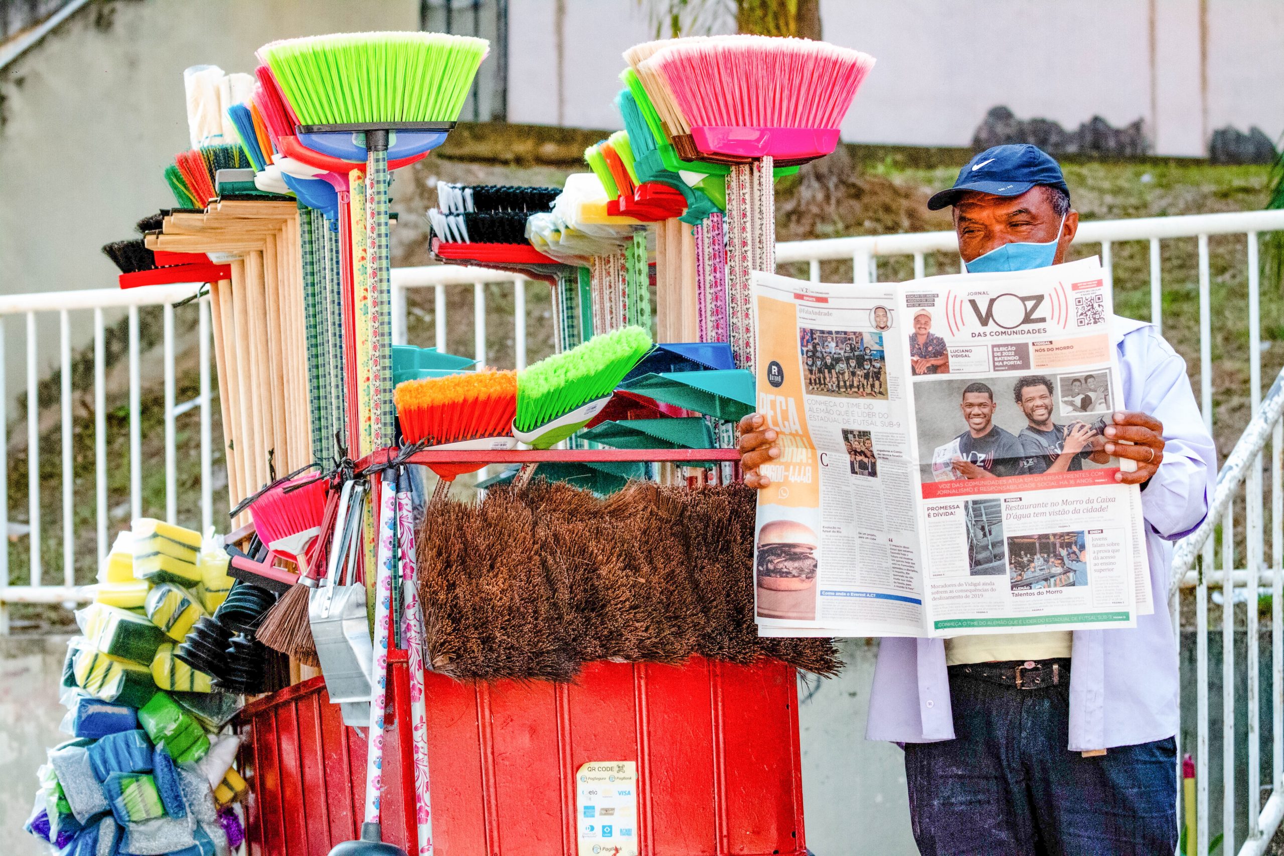 Figura conhecida nas ruas do Complexo do Alemão, o vassoureiro também exerce o costume de ler o nosso jornal impresso para se manter informado sobre tudo que acontece no seu território. Entre uma vassoura vendida e outra ele dá uma pausa pra ler seu jornal. Foto: Vilma Ribeiro
